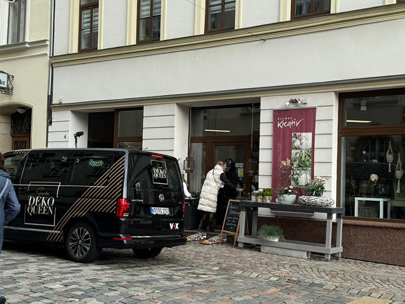 dekoqueen-guidos-vox-bei-blumen-kreativ-schwarzer-vox-bus-vor-tuer